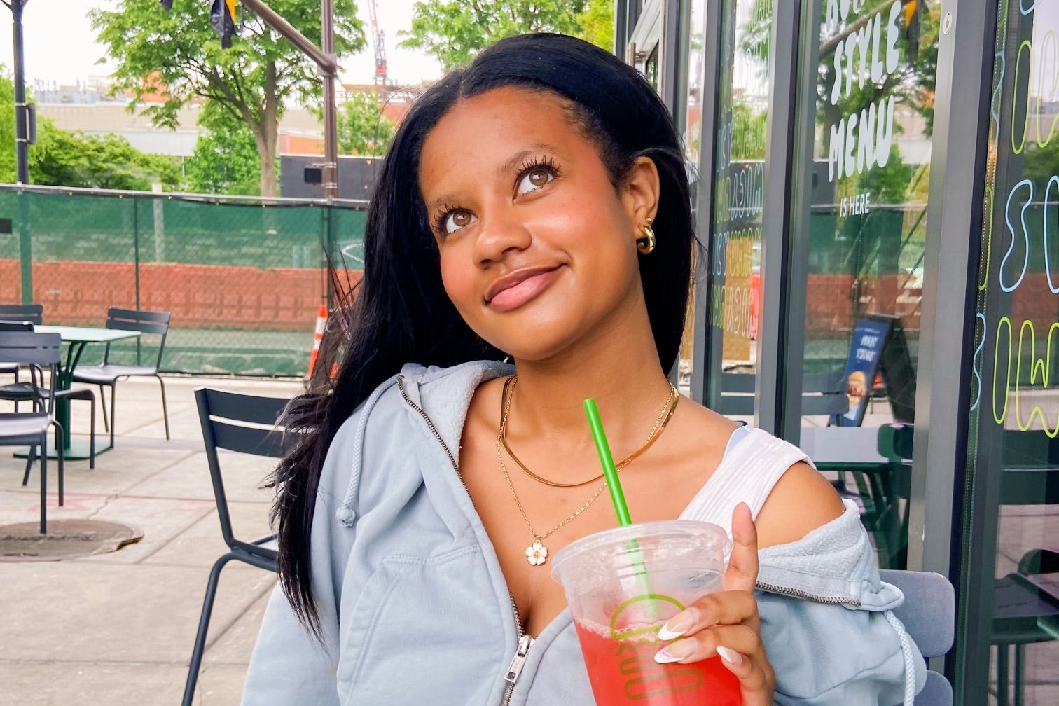 teenage girl wearing unique gold plated jewelry while holding drink