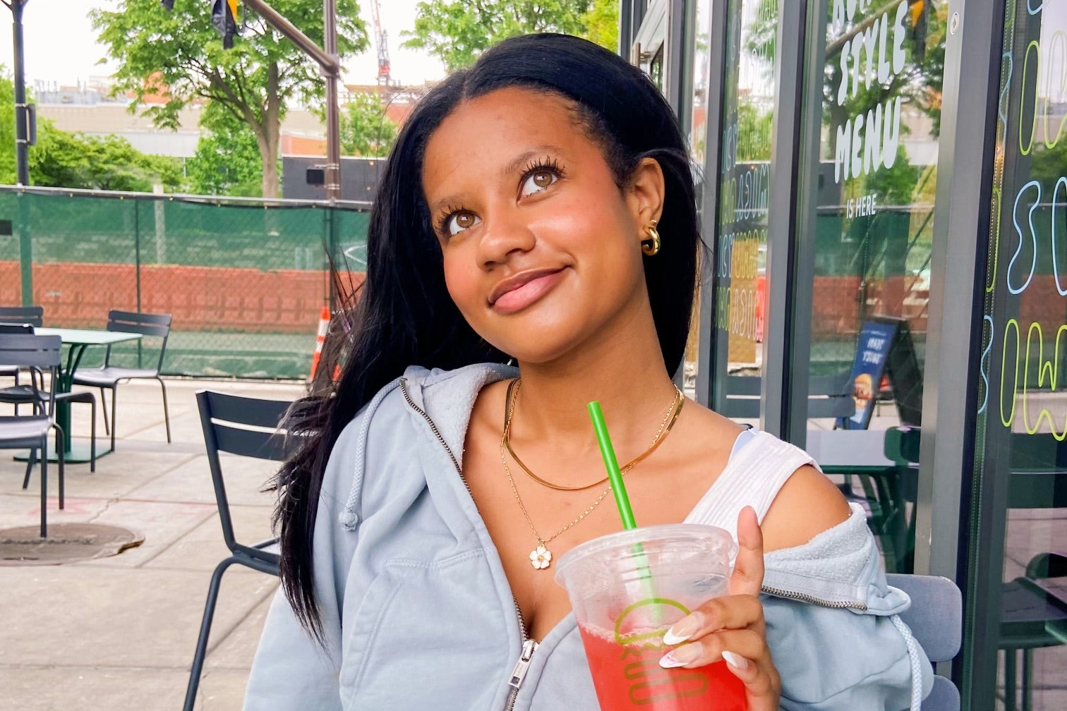 teenage girl wearing unique gold plated jewelry while holding drink 